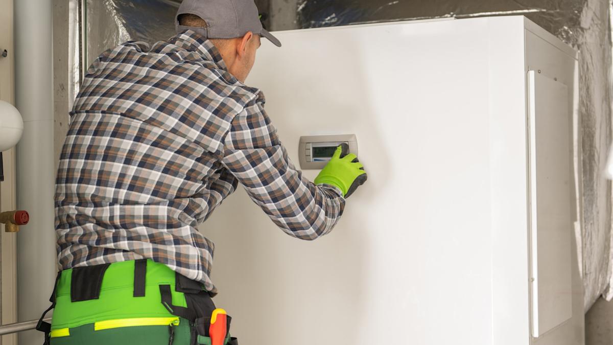 Technicien Altiora Confort réglant un thermostat de chauffage