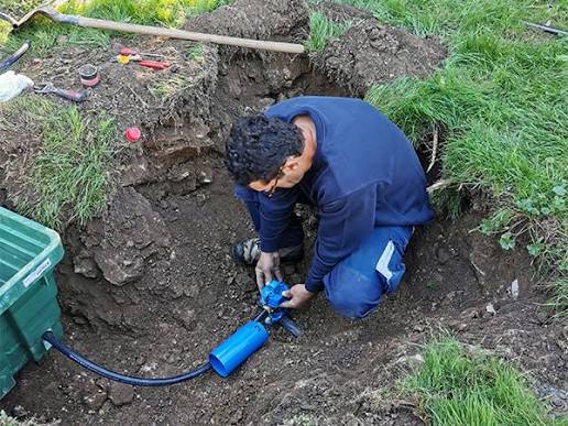 Technicien réparant une canalisation extérieure enterrée