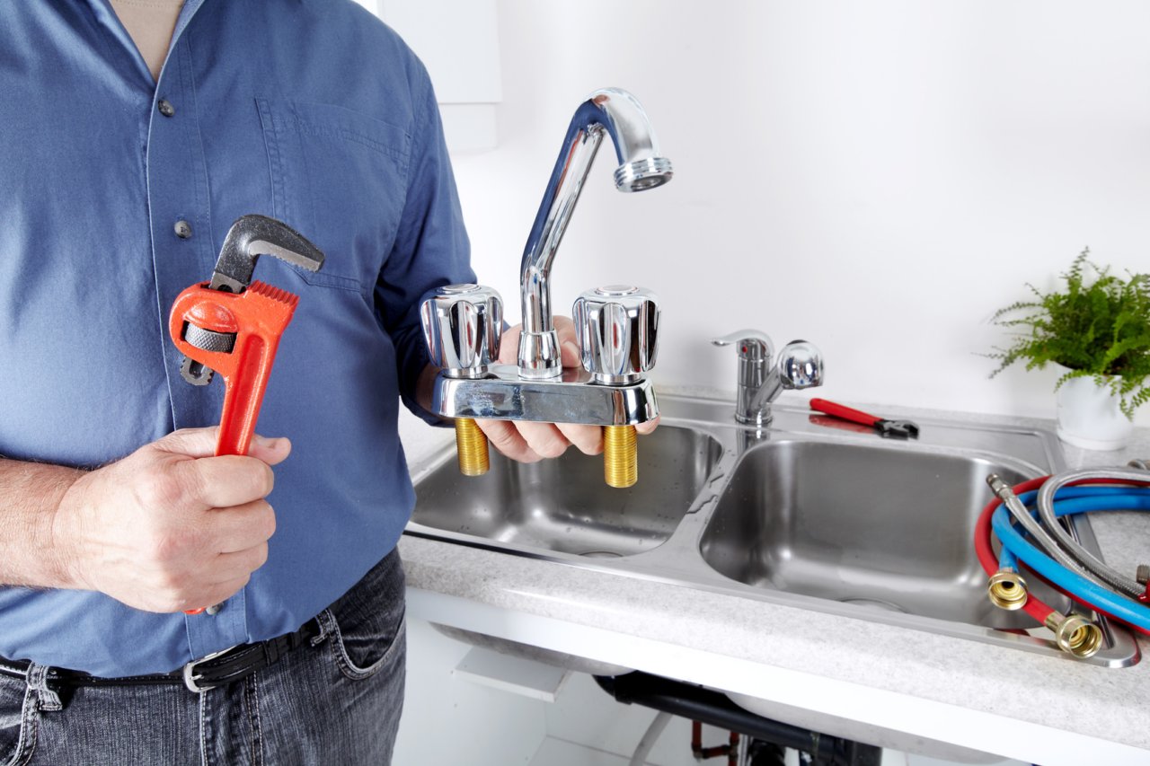 Plombier installant la robinetterie d'une cuisine