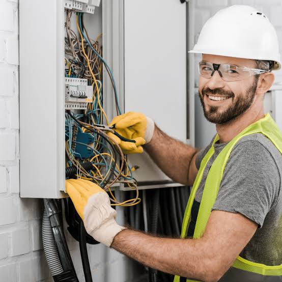 Électricien câblant un tableau électrique dans une construction neuve