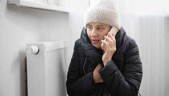 Personne au téléphone près d'un radiateur en panne