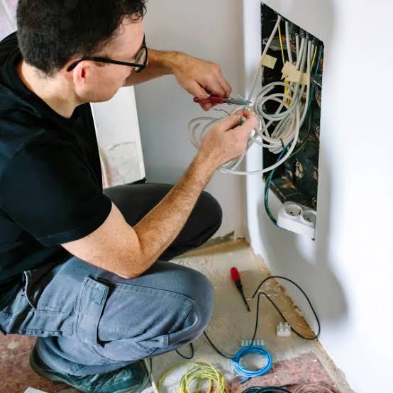 Technicien réparant un tableau électrique après un court-circuit